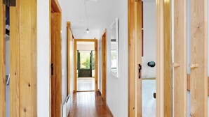 Un corridoio in legno con una porta in fondo che dà su una stanza con una finestra.