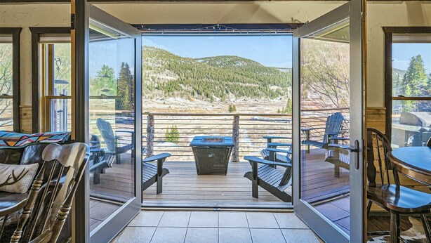 Quarto com uma grande porta de correr de vidro que dá para um deck externo com vista para uma paisagem montanhosa.