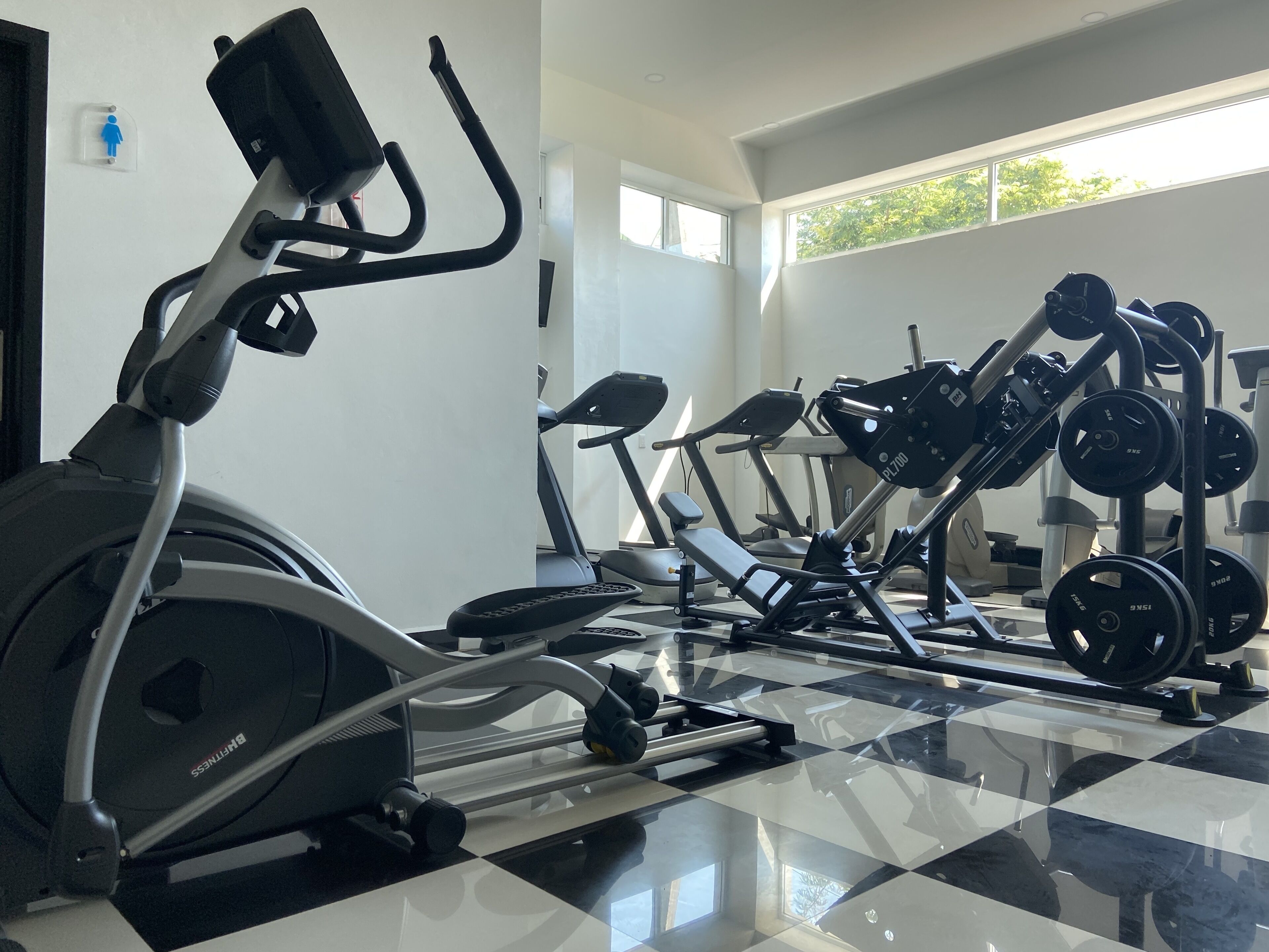 A gym with various exercise equipment, including an elliptical, treadmills, and weight machines.