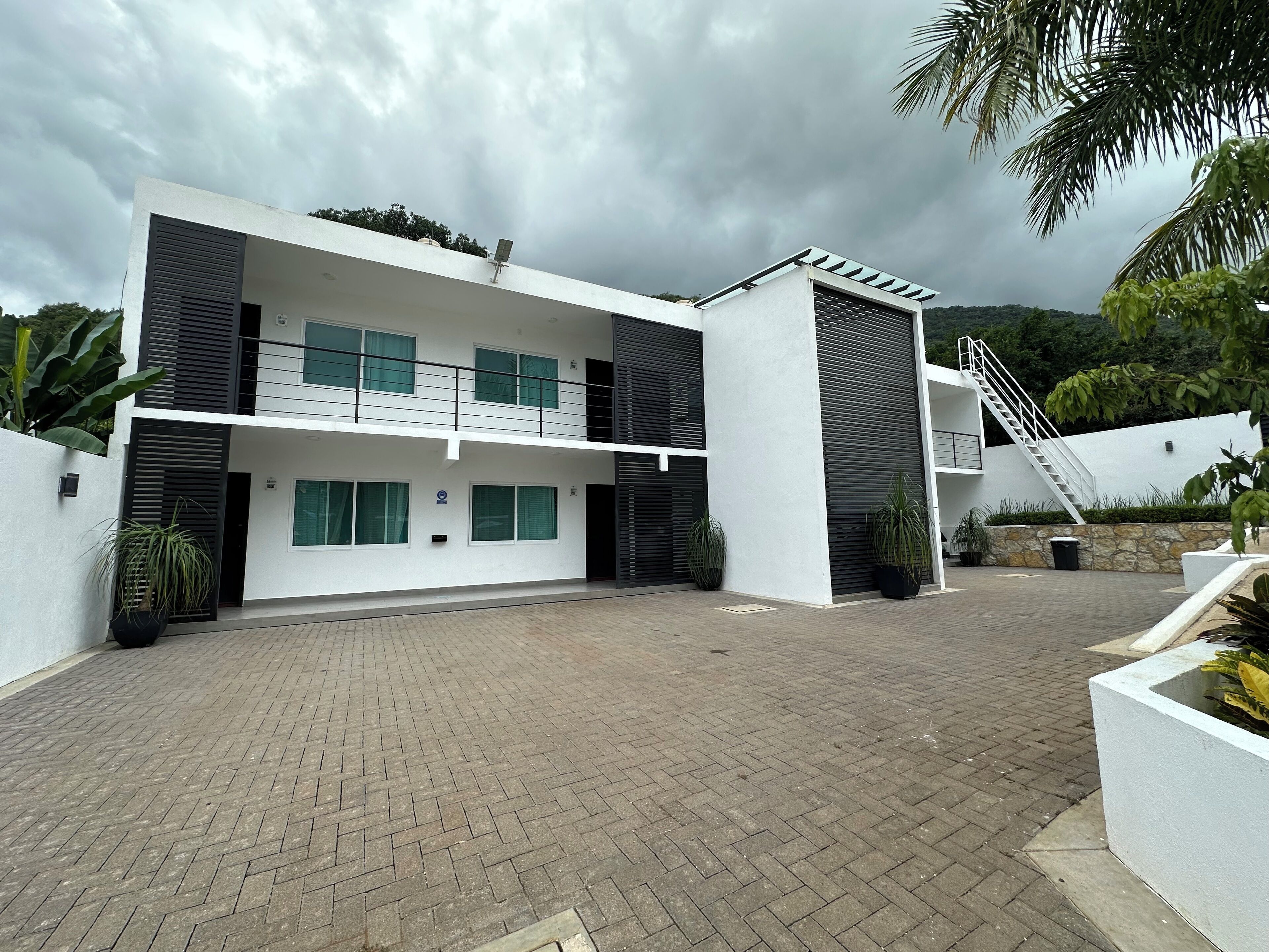 A modern two-story building with a flat roof, large windows, and a central staircase.