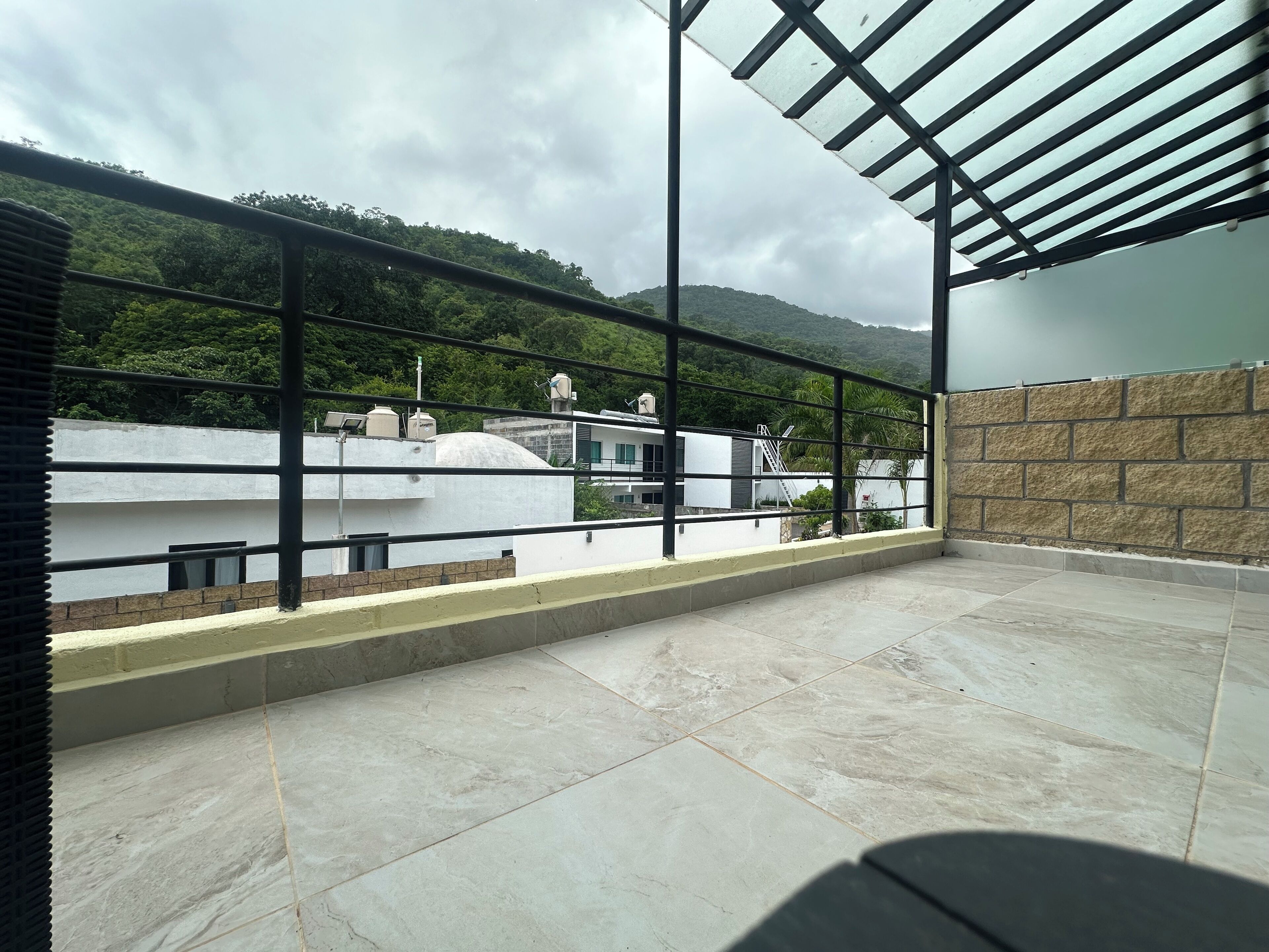 Un balcón con vistas a una ladera verde y un edificio blanco.