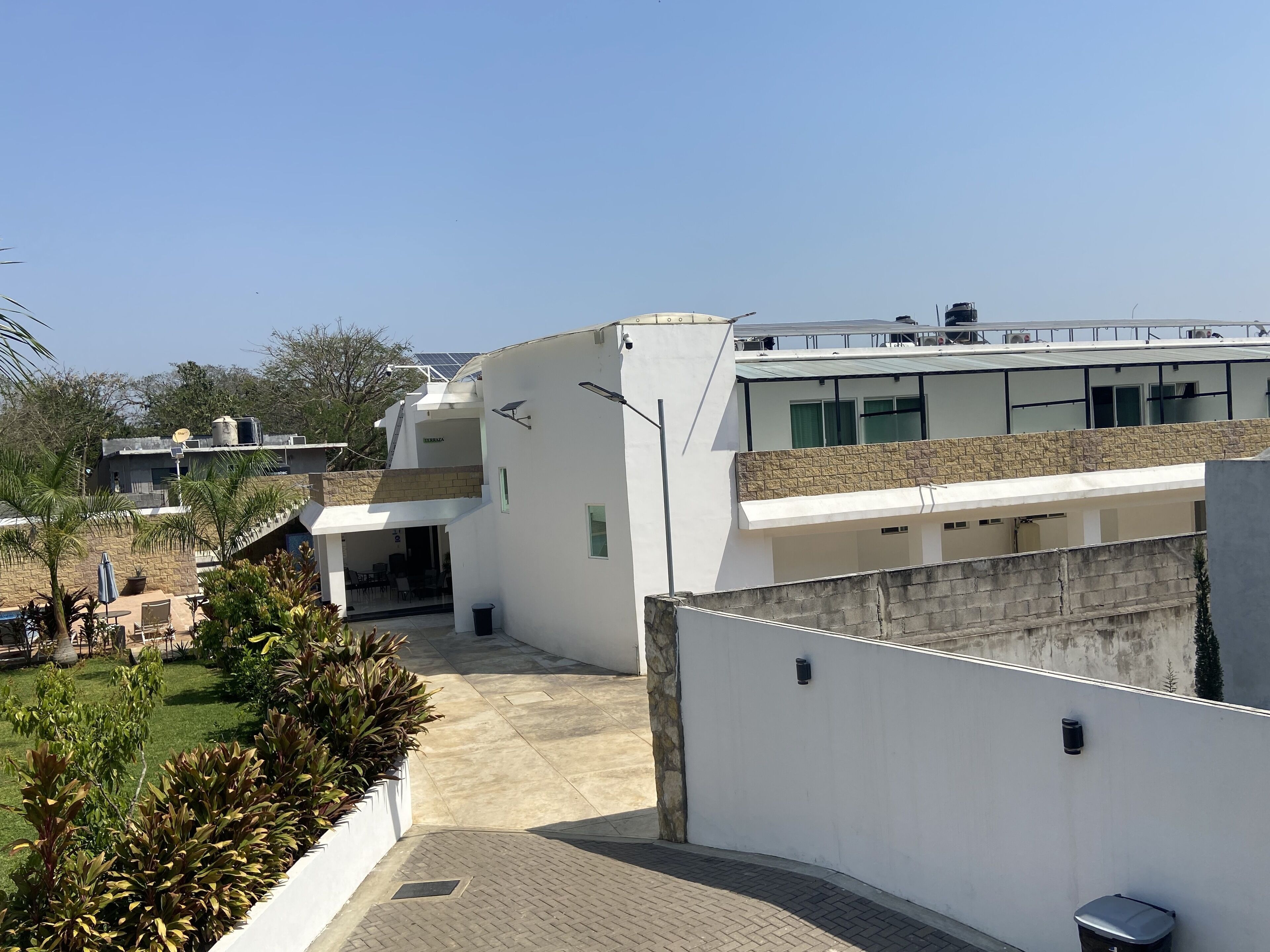 A modern building with a flat roof, solar panels, and a covered outdoor seating area.
