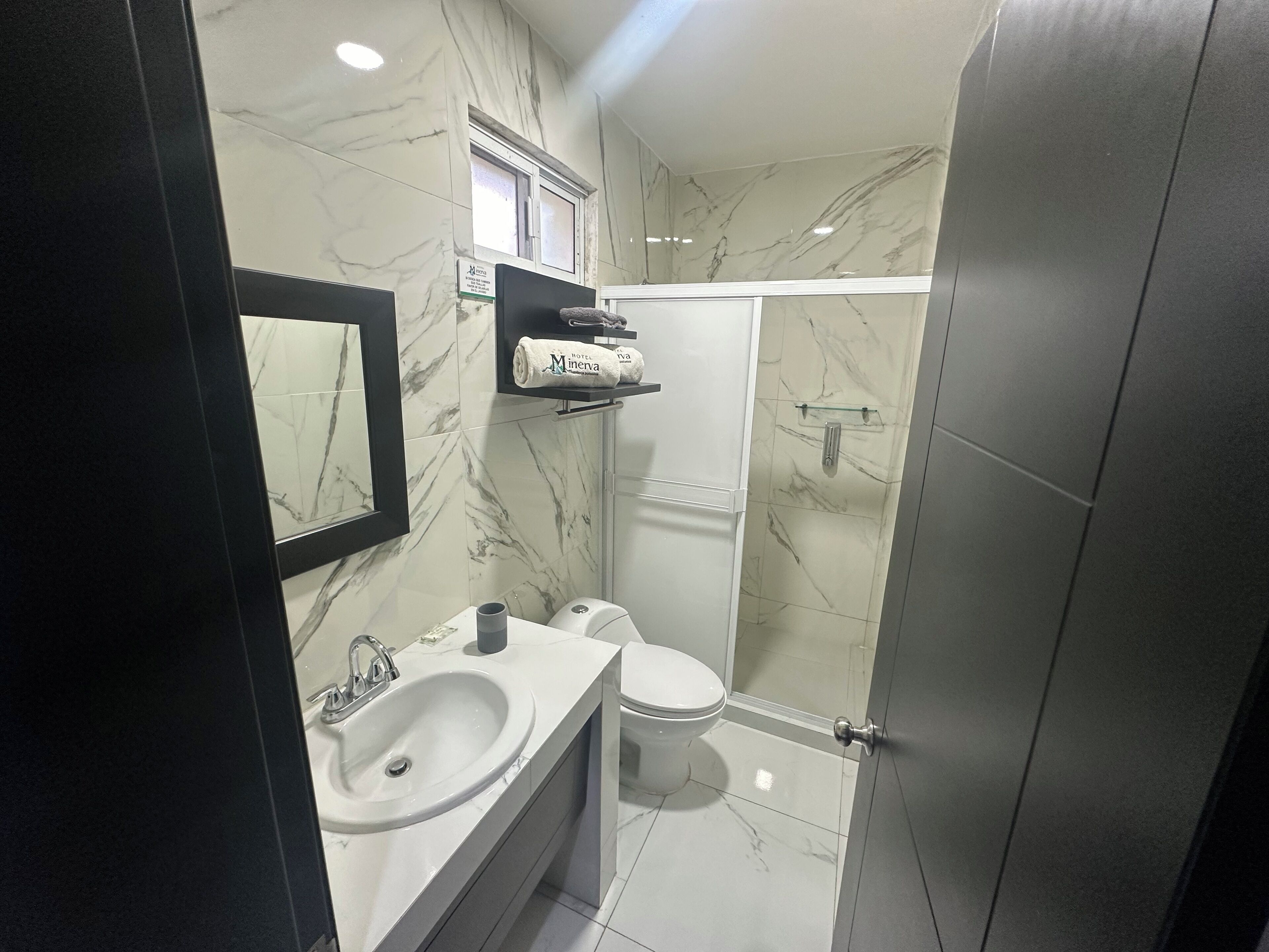 A modern bathroom with a marble sink, toilet, and shower.
