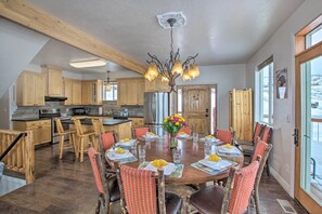 A spacious kitchen with wooden cabinets, a central island, and a dining area with a round table and chairs. - Dinosaur Point Lodge (Garden City)
