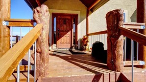 Un escalier en bois mène à une porte surmontée d’une statue d’ours et d’une lanterne.