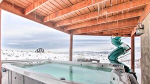 Un bain à remous avec vue sur un paysage enneigé et un chalet situé au loin.