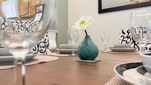 Een eettafel met een bloevas, borden en glazen.