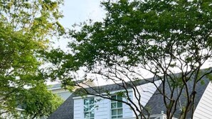 Uma casa branca com varanda coberta, número 604, com guarda-corpo, vasos de plantas e área de estar externa.