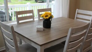 Una mesa de comedor con un jarrón de flores amarillas, rodeada de sillas blancas.
