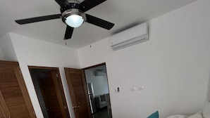 A bedroom with a bed, pillows, a ceiling fan, and an air conditioning unit. - Beautiful Beach Condo on the sand (Cabarete)