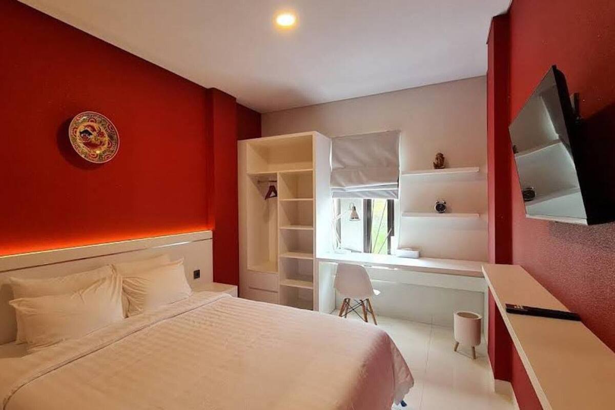 A bedroom with a bed, a wardrobe, a desk, a chair, and a television.