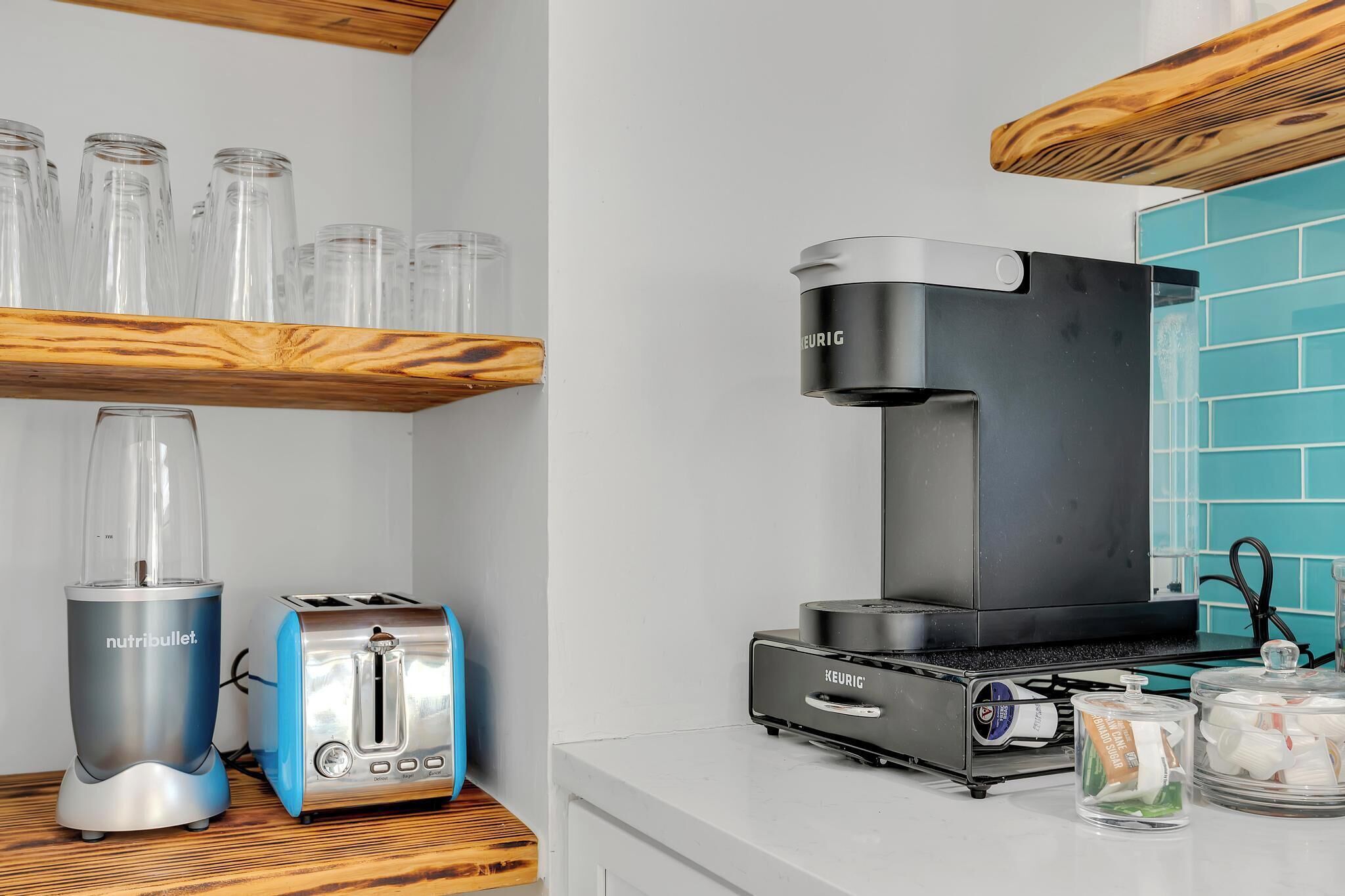 Een keuken met een Keurig koffiezetapparaat, een broodrooster en een blender op het aanrecht.