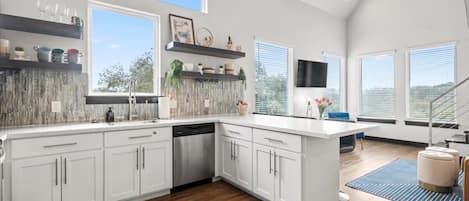 Enjoy cooking in this well-equipped kitchen with a central island, white cabinetry, and a dishwasher.