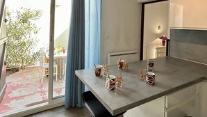 Una cocina moderna con una mesa de comedor para cuatro personas, un amplio ventanal con cortinas azules y vistas al exterior.