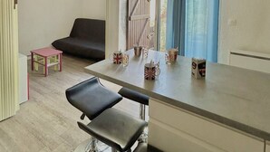 Un espacio habitable pequeño y de concepto abierto, con un sofá, una mesita con tazas y una encimera de cocina.
