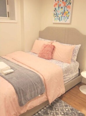Cozy retreat with a plush bed, adorned with a duvet and throw blanket, and a stylish artwork above.