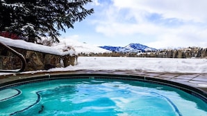 A swimming pool with clear blue water, surrounded by snow-covered ground and mountains in the background. - Classy, contemporary, cozy, Sun Valley condo with Resort Amenities (Sun Valley)
