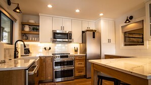 A modern kitchen with white cabinets, stainless steel appliances, and a marble countertop. - Classy, contemporary, cozy, Sun Valley condo with Resort Amenities (Sun Valley)