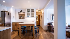 A modern kitchen with wooden cabinets, a built-in island with bar stools, and a refrigerator. - Classy, contemporary, cozy, Sun Valley condo with Resort Amenities (Sun Valley)