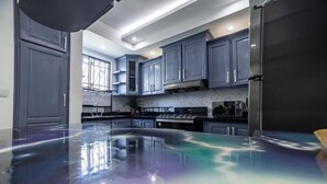 Una cocina moderna con gabinetes grises, un refrigerador de acero inoxidable y un piso brillante.