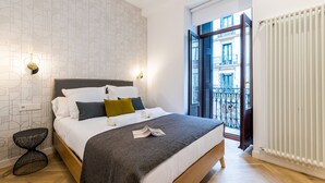 Un dormitorio moderno con una cama grande, un diseño de pared original y vistas de la ciudad a través de una puerta abierta.