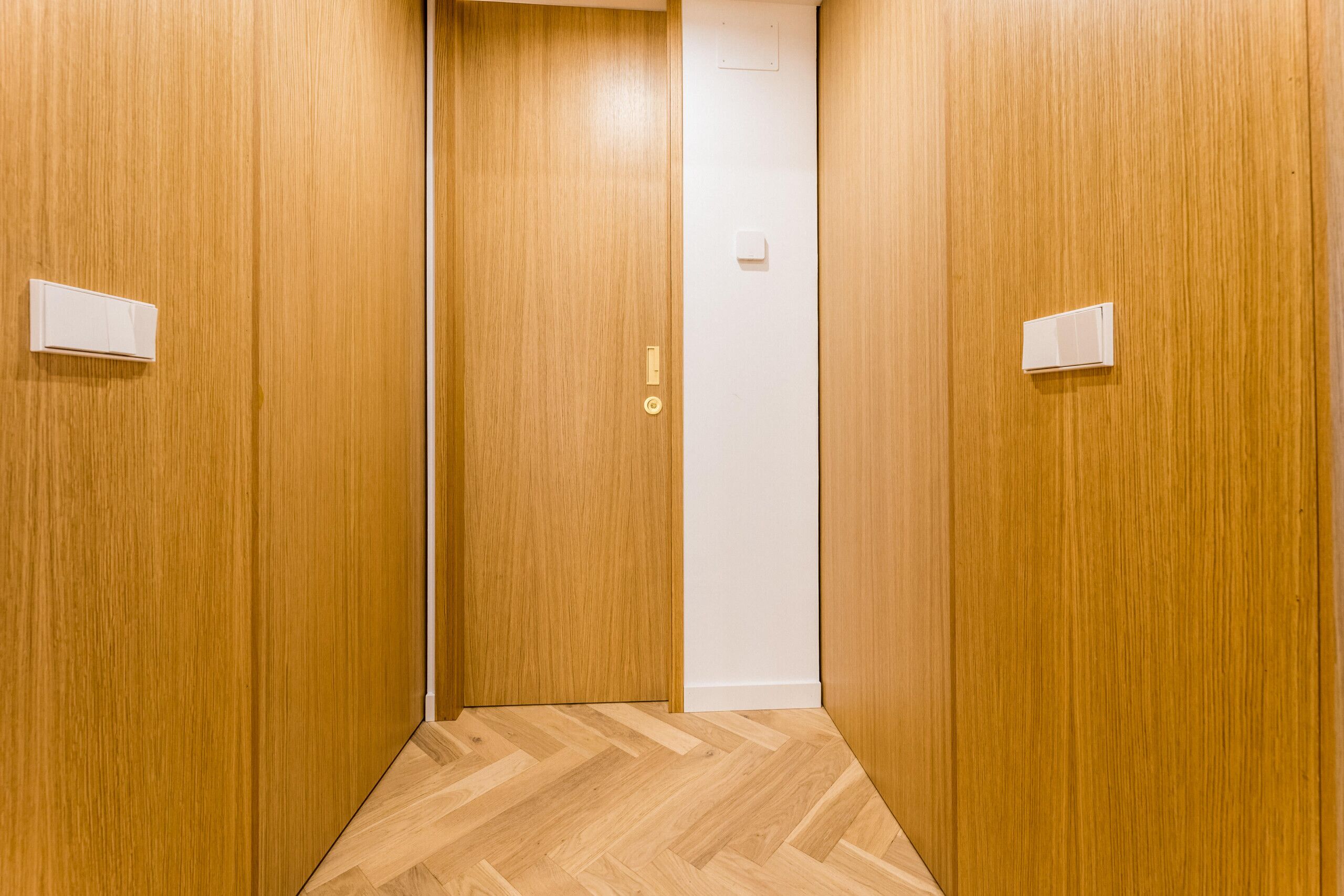 A hallway with wooden walls and a herringbone floor pattern.