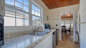 Una cocina con encimeras de granito, lavamanos de acero inoxidable y techo de madera.