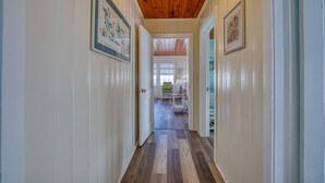 Un pasillo con techo de madera y paredes blancas que conduce a un comedor con mesa y sillas.
