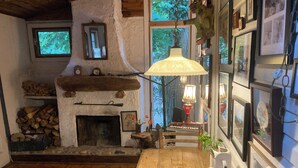 A cozy room with a fireplace, wooden flooring, and a table with a lamp.