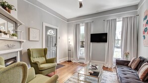 A living room with a fireplace, green armchairs, a dark sofa, and a flat-screen TV.
