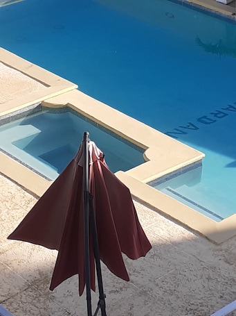 A pool with a clear view of the pool area, including a section of the pool deck and a red umbrella.