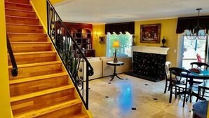 A staircase leading to a living area with a fireplace, a dining table, and a sofa.