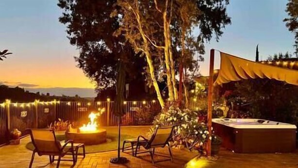 An outdoor patio area with a fire feature, seating, and a hot tub.