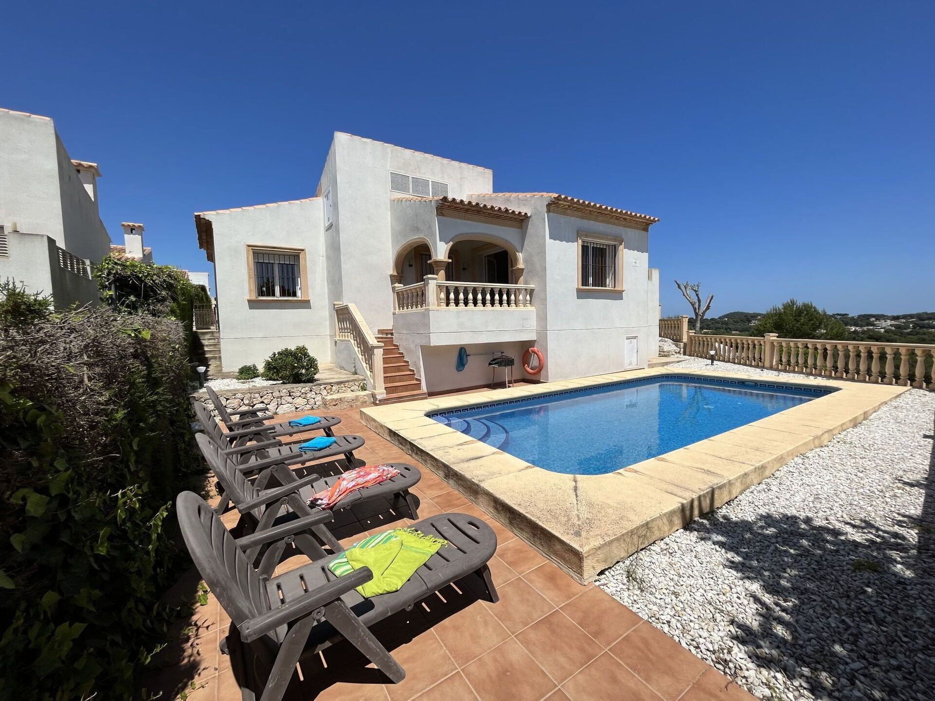 Une villa moderne dotée d’une piscine, d’un espace salon extérieur et d’un escalier menant à un balcon.