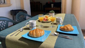 Ein Esstisch mit Croissants, Obst und Orangensaft.