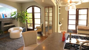Une cuisine moderne équipée d’une cuisinière à gaz, d’un coin repas avec une chaise blanche et d’une grande fenêtre laissant entrer la lumière naturelle.