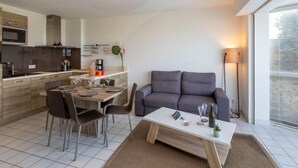 Ett modernt vardagsrum med en grå soffa, ett soffbord och en matplats med stolar och ett bord.
