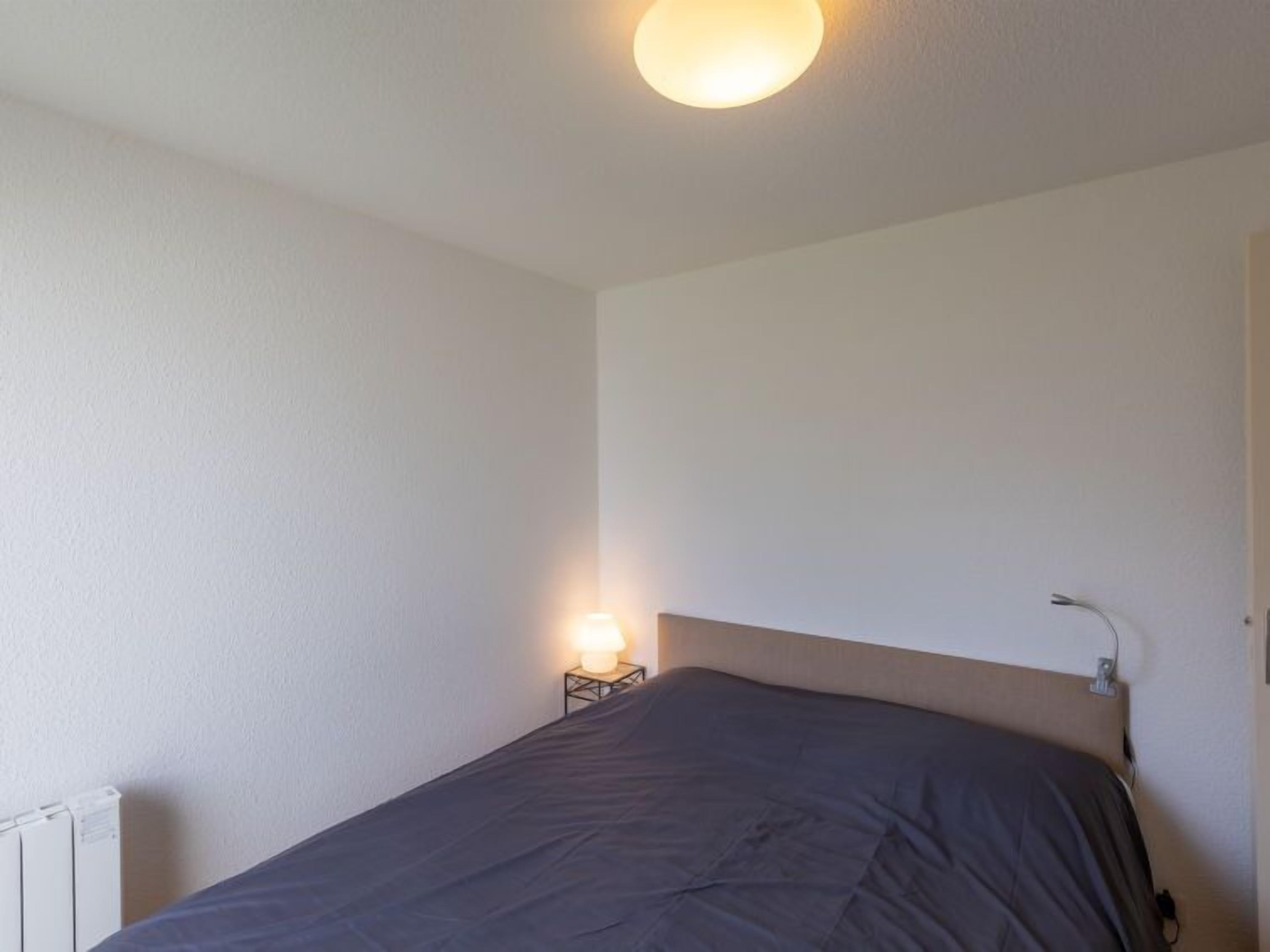 Ein Schlafzimmer mit Bett, Nachttischlampe und Heizkörper.