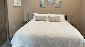 A bedroom with a large bed, two bedside tables, and three wall-mounted paintings. - PERFECT 2 bedroom, 1 bath Condo (Helena)