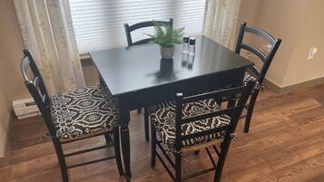 A dining table with four chairs, a potted plant, and salt and pepper shakers.