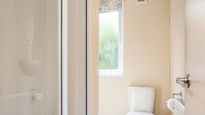 A bathroom with a toilet, a window, and a shower door. - 1 bedroom accommodation in Mullion Cove, Helston (Mullion Cove, Helston)