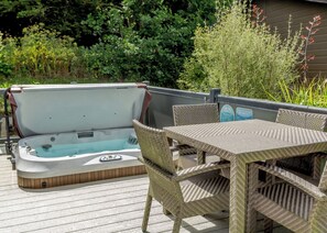A hot tub with a control panel, surrounded by wicker furniture on a wooden deck. - 1 bedroom accommodation in Mullion Cove, Helston (Mullion Cove, Helston)