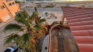 En fastighet vid kusten med utsikt över havet, ett palme och ett tak täckt med takpannor.