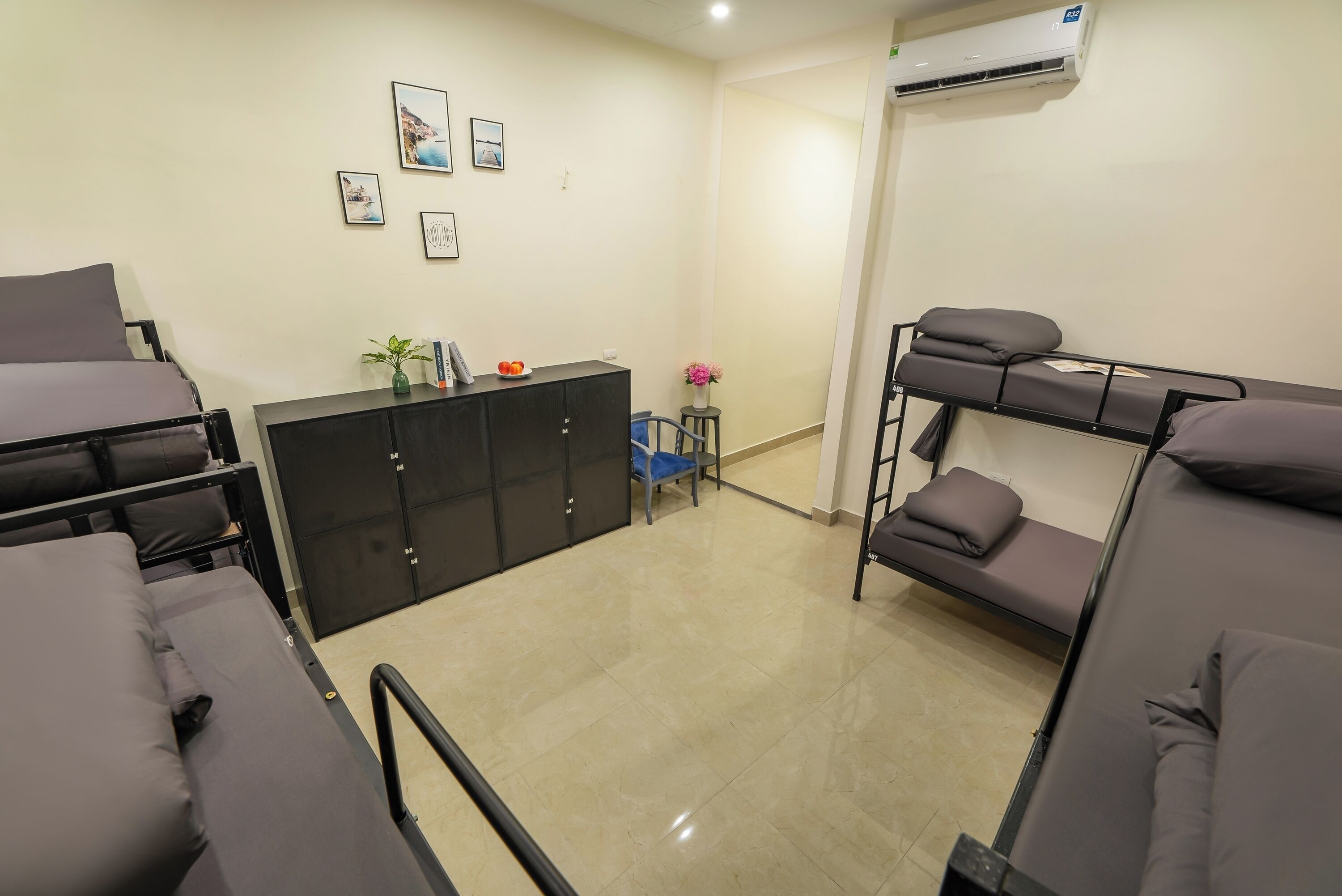 A dormitory room with bunk beds, a desk, and a chair.