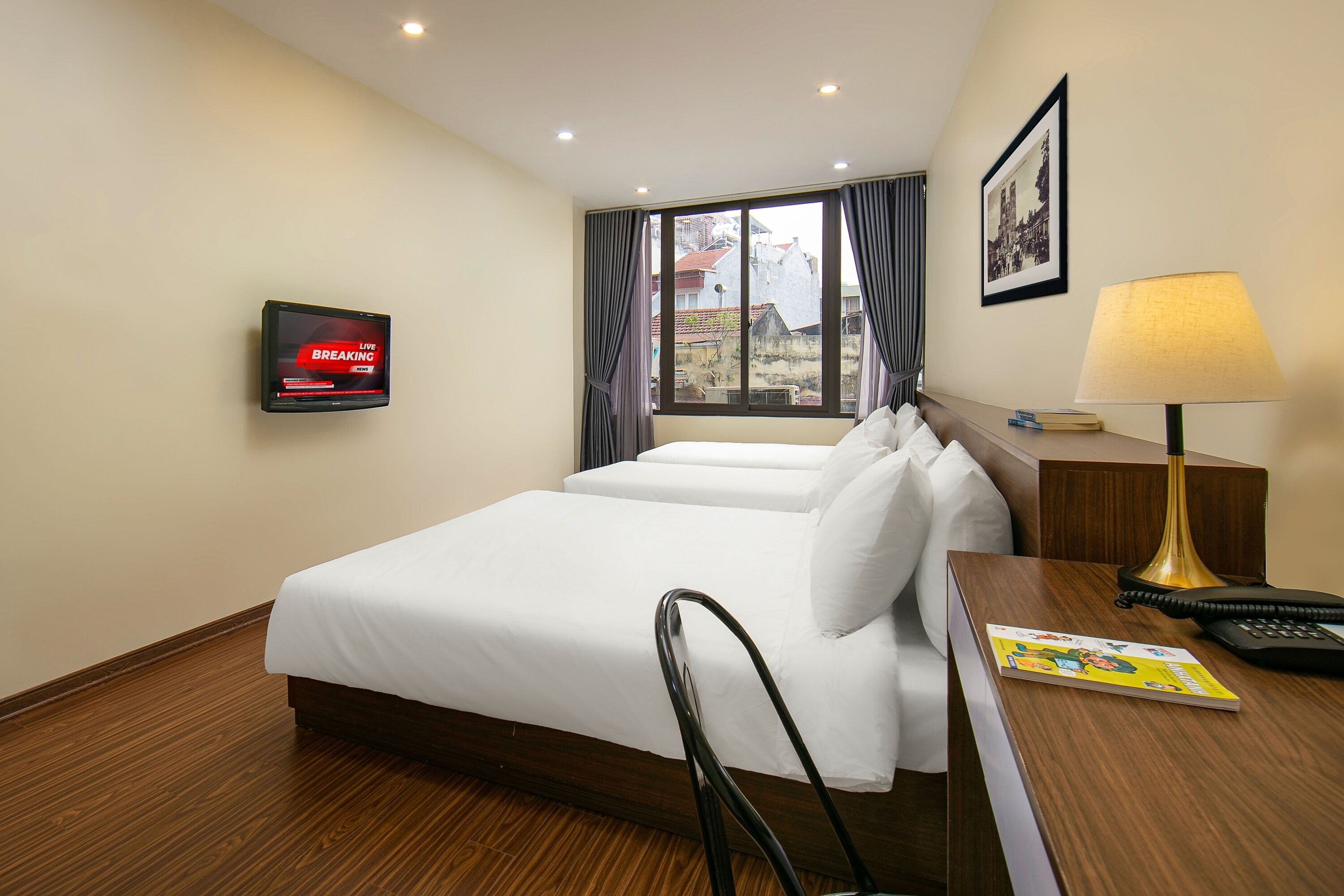 A hotel room with a bed, a desk, a lamp, a TV, and a window with curtains.