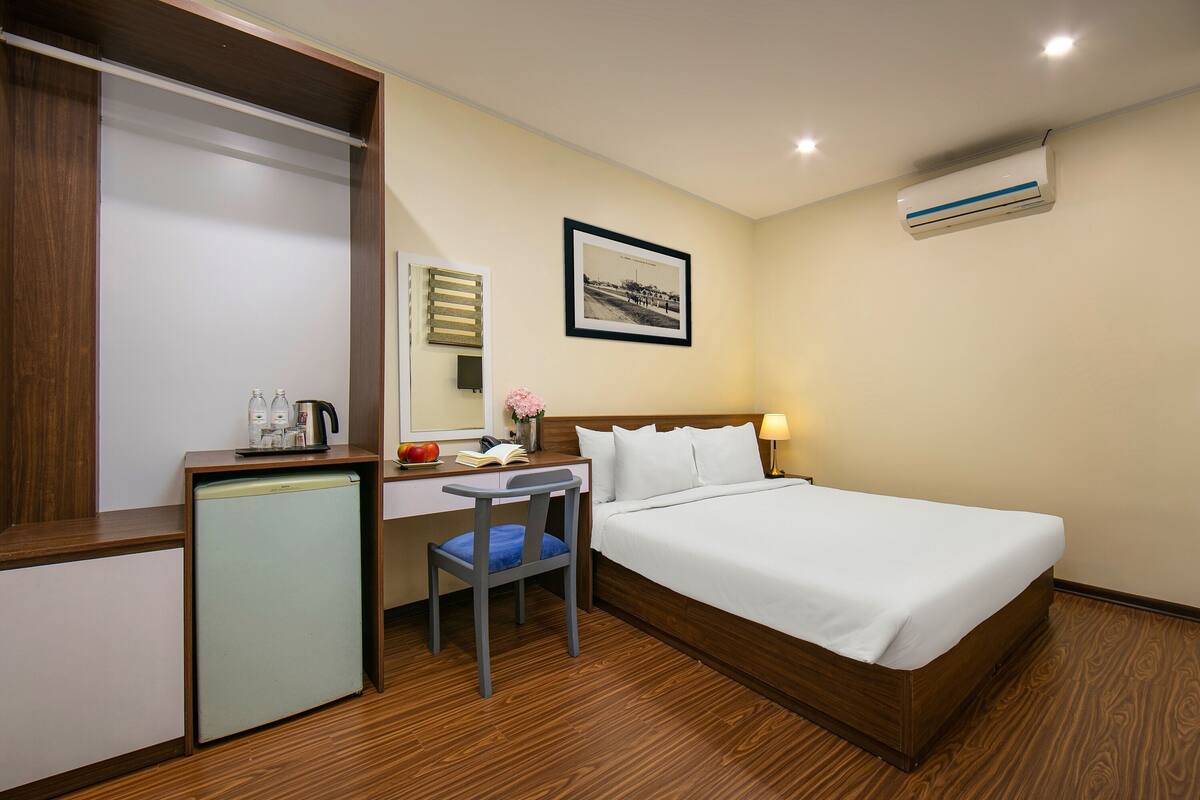 Une chambre d’hôtel équipée d’un lit, d’un bureau, d’une chaise et d’un petit réfrigérateur.