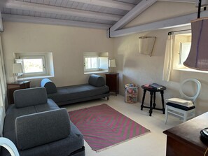 A compact living space with a sofa, a small table, a chair, a lamp, and a window.