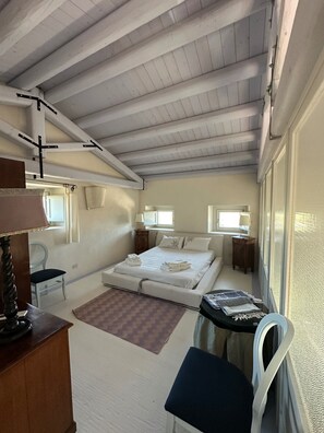 Quarto compacto com cama, escrivaninha, cadeira e mesa pequena.