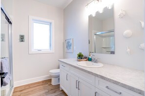 Une salle de bain moderne avec un meuble-lavabo blanc, un grand miroir et une fenêtre.