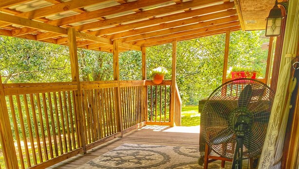 A hot tub in a wooden deck area with a view of greenery.